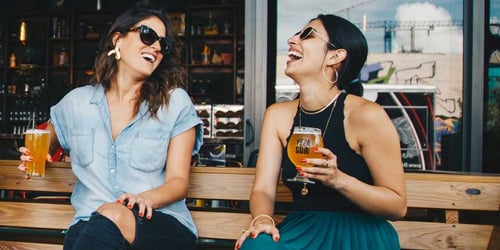 Zwei Frauen lachen und haben Cocktails in einer Gastronomie