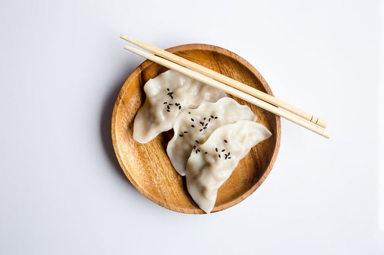 Dumplings serviert auf einem Bambusteller mit Essstäbchen