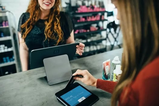 Händler hält einen Geschenkgutschein im Ladengeschäft – Gutschein-Marketing im Einzelhandel