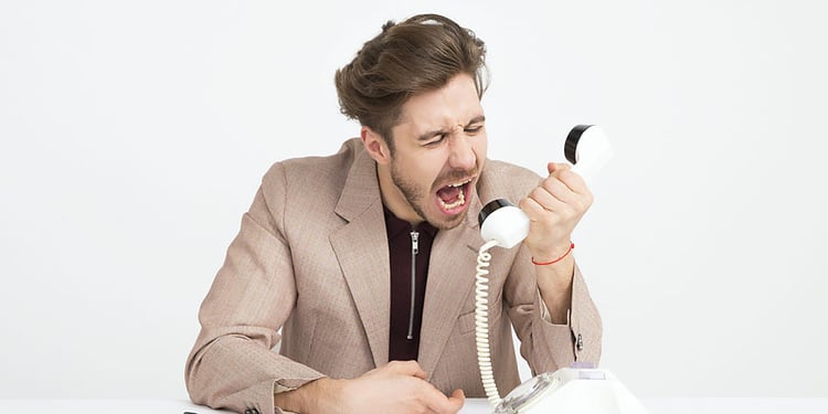 Mann im Anzug schreit wütend in ein Telefon