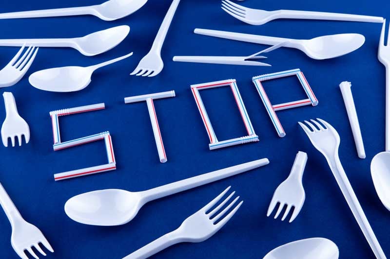 Wegwerfbesteck aus Plastik und das Wort STOP aus Plastiktrinkhalmen