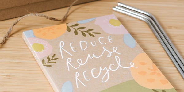 Ein Notizbuch und Metallstrohhalm als Zero Waste Produkte